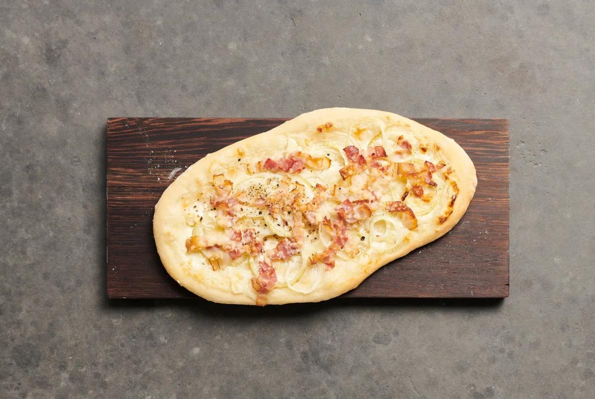 Pizza alsaziana aus der Kategorie Gebäck salzig. Das fertige Gericht schön angerichtet und fotografiert aus Vogelperspektive (Food Fotografie). Serviervorschlag, Original Tiptopf Rezept, aus dem bekanntesten Kochbuch der Schweiz
